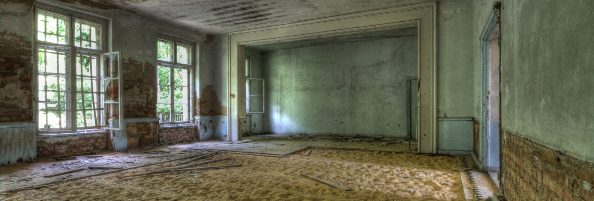 Verlassener Raum mit Sand und alten Fenstern.